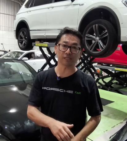 Toshio ao lado de Porsche em manutenção